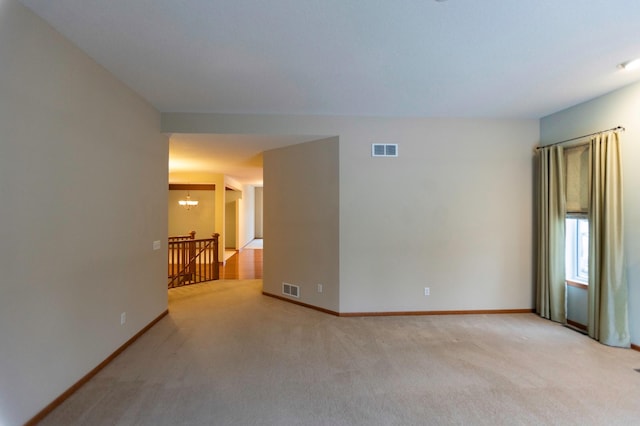 unfurnished room with a chandelier, carpet, visible vents, and baseboards