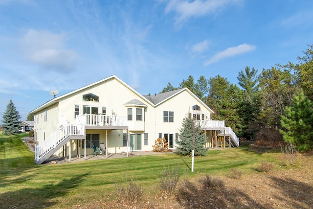 rear view of house with stairs, a deck, and a lawn