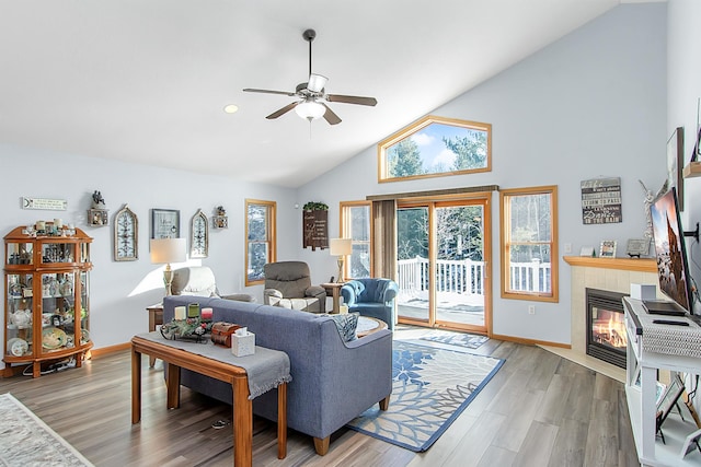 living room featuring baseboards, a fireplace, light wood finished floors, and ceiling fan