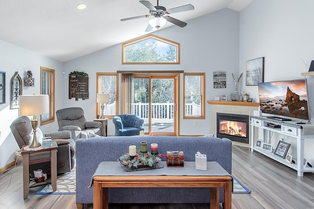 living room with high vaulted ceiling, a fireplace, wood finished floors, a ceiling fan, and baseboards