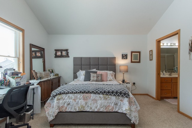 bedroom featuring light colored carpet, vaulted ceiling, baseboards, and ensuite bathroom