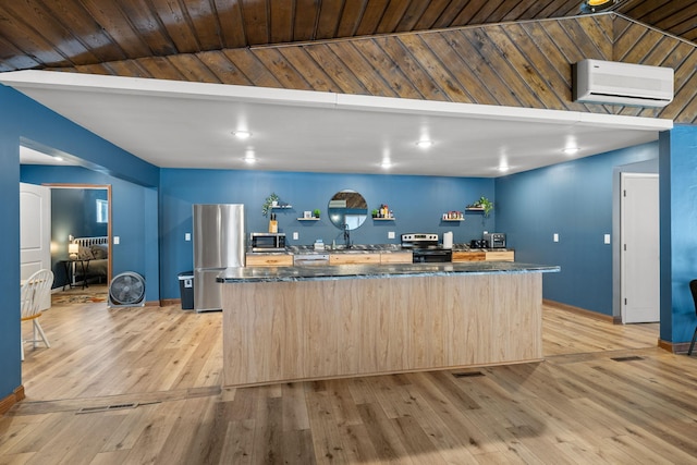 interior space featuring an AC wall unit, light hardwood / wood-style flooring, stainless steel appliances, and dark stone counters