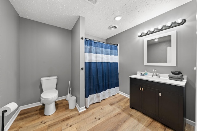 bathroom with hardwood / wood-style flooring, vanity, toilet, a textured ceiling, and a shower with shower curtain