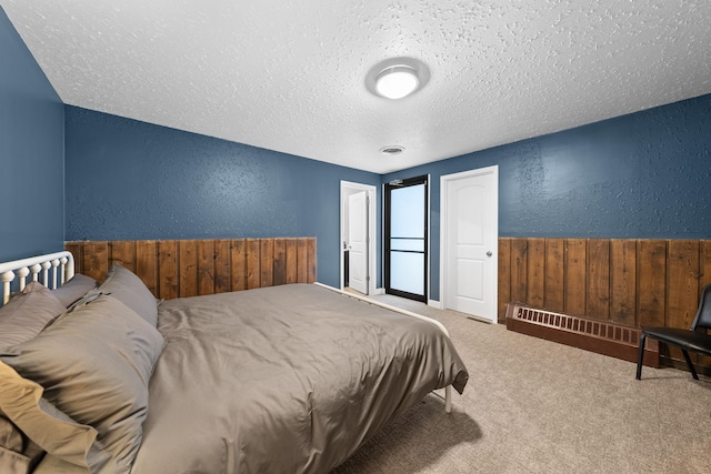 carpeted bedroom with a textured ceiling and wood walls