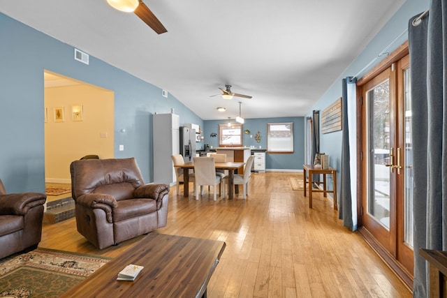 living room featuring ceiling fan, lofted ceiling, and light hardwood / wood-style flooring