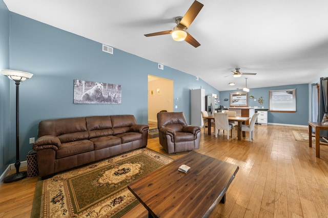 living room with vaulted ceiling, ceiling fan, and light wood-type flooring