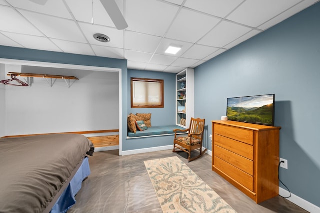 bedroom featuring a drop ceiling and concrete flooring