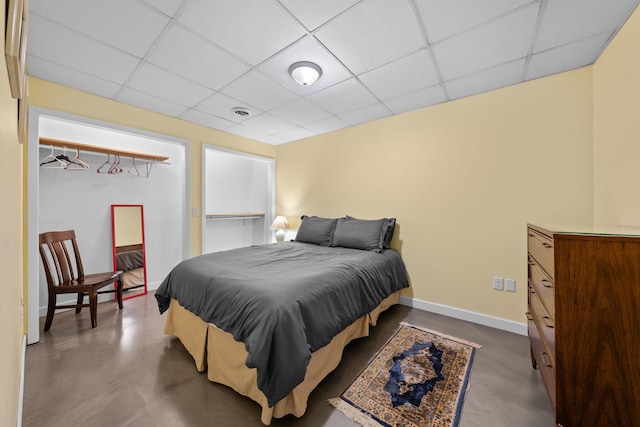 bedroom with a paneled ceiling and concrete floors