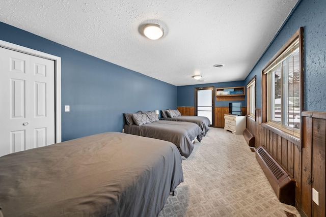 carpeted bedroom featuring a textured ceiling, wood walls, a wainscoted wall, and visible vents