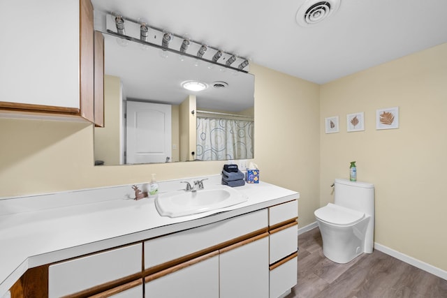 bathroom featuring toilet, wood finished floors, vanity, visible vents, and baseboards