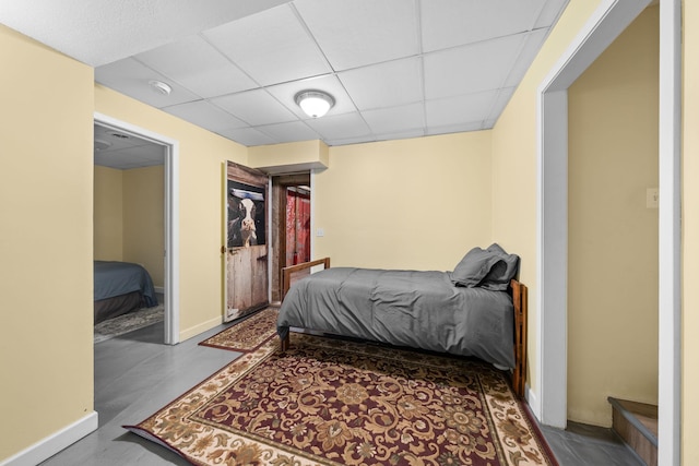 bedroom with a paneled ceiling and baseboards