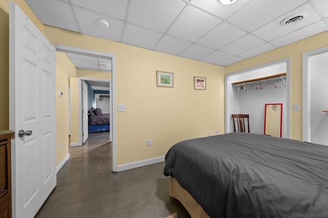 bedroom featuring a paneled ceiling, baseboards, visible vents, and concrete flooring