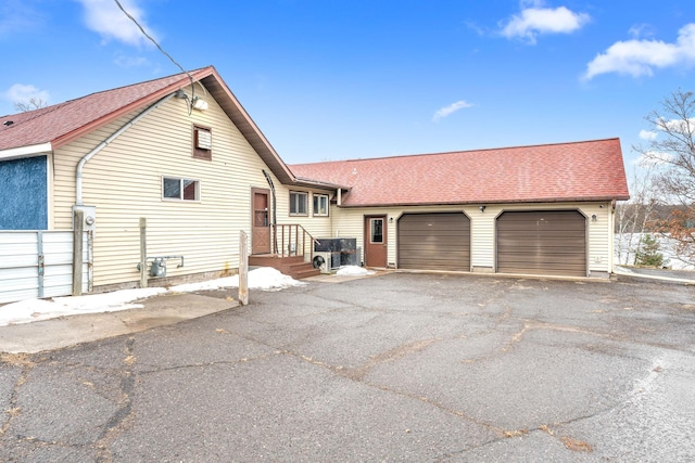 view of front facade with a garage, driveway, and a shingled roof