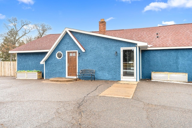 rear view of property with a patio, fence, roof with shingles, stucco siding, and a chimney