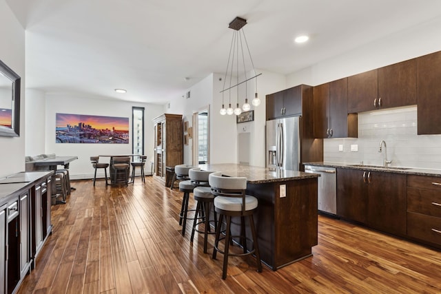 1240 2nd St Unit 704, Minneapolis, MN 55415 - kitchen with stainless steel appliances, a sink, a kitchen bar, dark wood-style flooring, and dark brown cabinetry