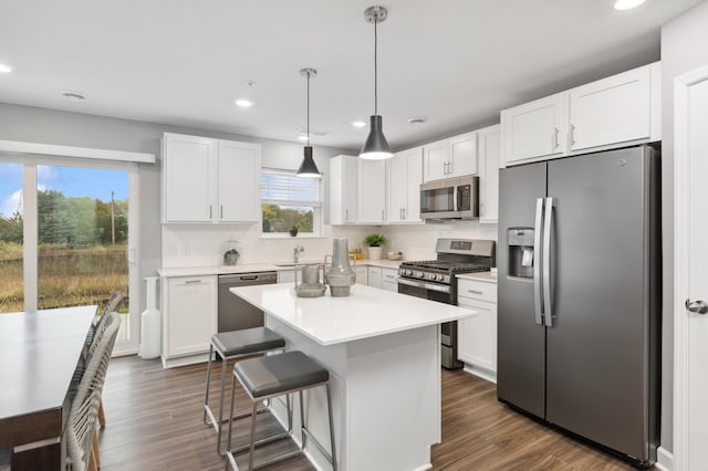 kitchen featuring white cabinetry, decorative light fixtures, stainless steel appliances, and a center island