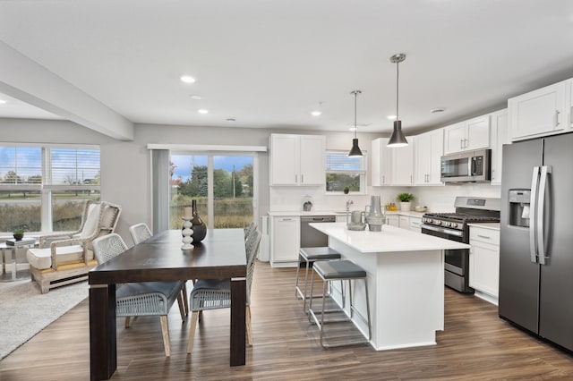 kitchen featuring pendant lighting, stainless steel appliances, a kitchen island, and white cabinets