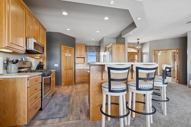 kitchen featuring recessed lighting, stainless steel appliances, light countertops, a center island, and decorative light fixtures