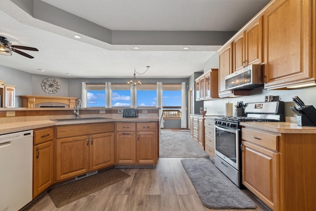 kitchen featuring appliances with stainless steel finishes, light countertops, a sink, and light wood-style flooring