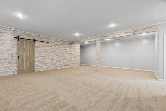 finished below grade area featuring ornamental molding, a barn door, carpet, and recessed lighting