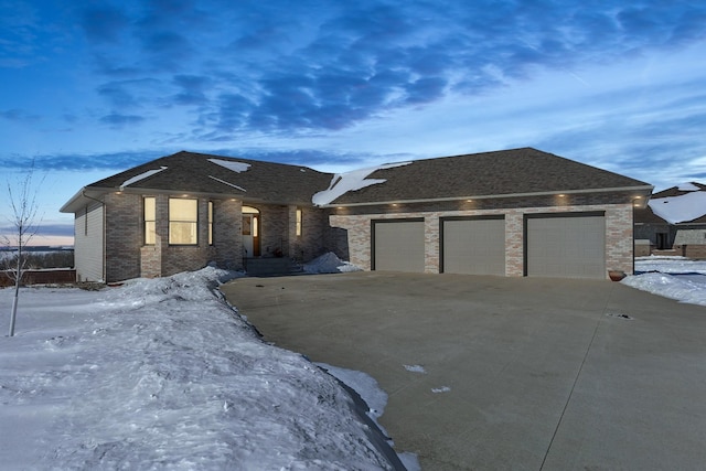 single story home with driveway, brick siding, and an attached garage
