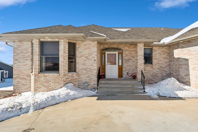 entrance to property with brick siding and roof with shingles