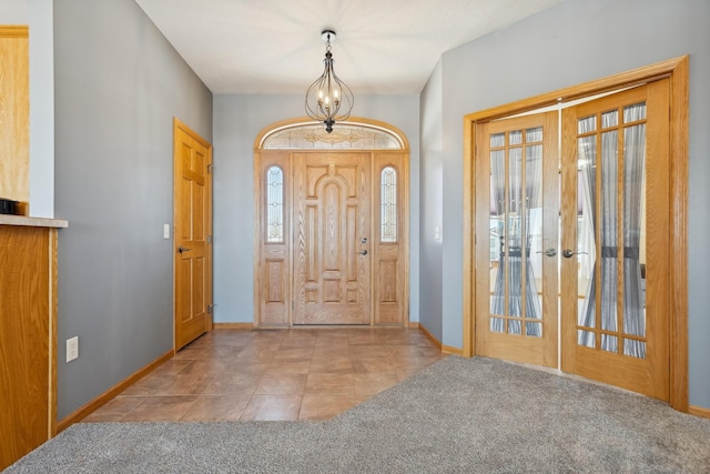 tiled foyer entrance featuring french doors, baseboards, and carpet
