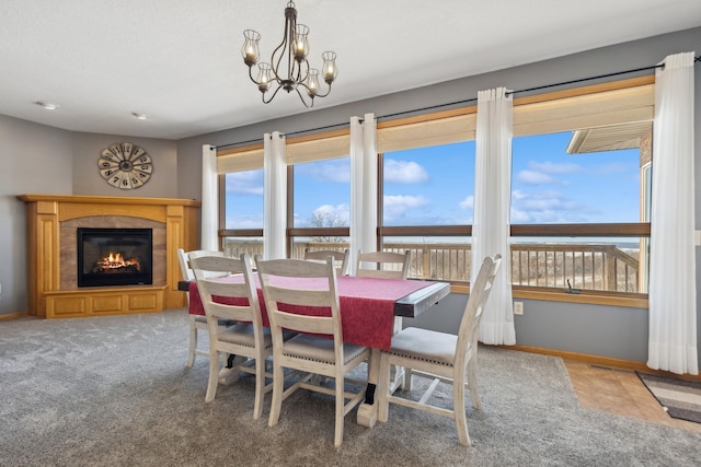 carpeted dining area with baseboards, an inviting chandelier, and a glass covered fireplace
