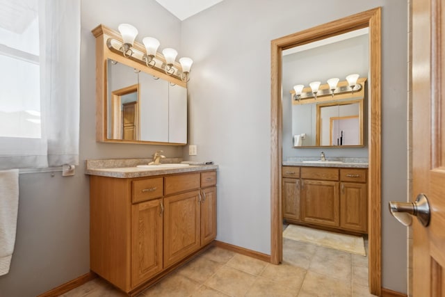 full bath featuring a sink, baseboards, two vanities, and tile patterned floors
