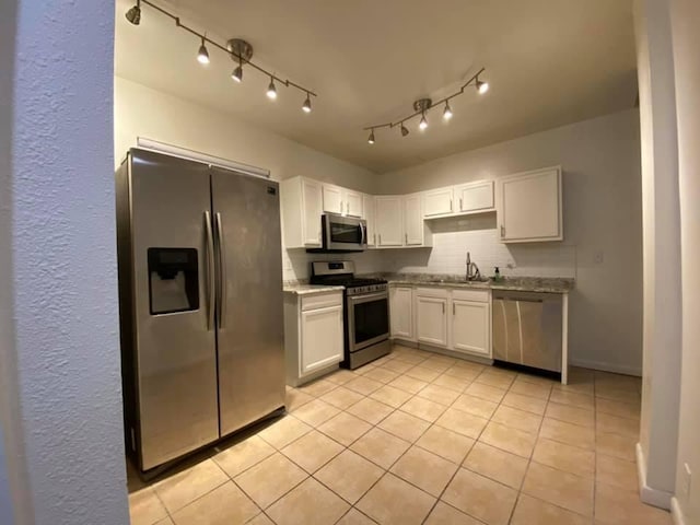 kitchen with light tile patterned flooring, stainless steel appliances, a sink, white cabinets, and tasteful backsplash