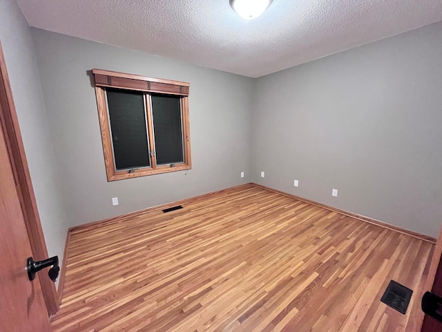 unfurnished room featuring light wood-type flooring and a textured ceiling