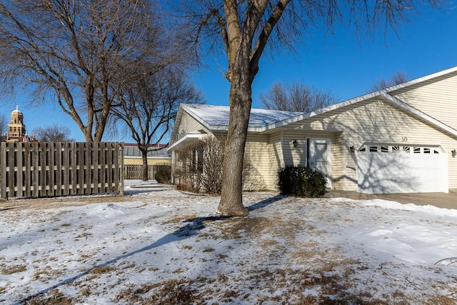 snow covered property with a garage