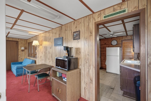 interior space featuring ceiling fan, wooden walls, and sink