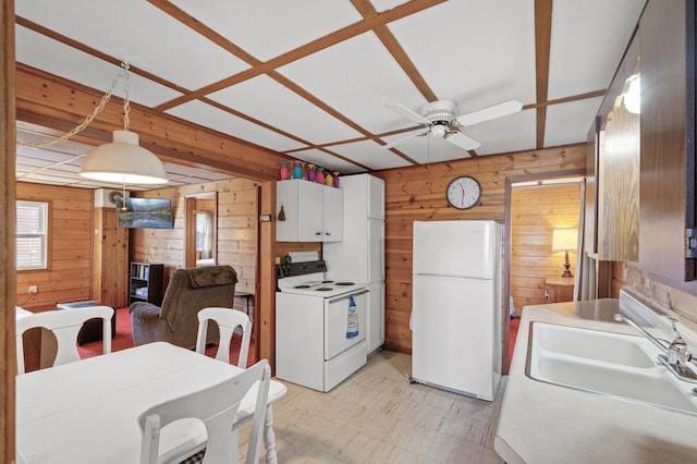 kitchen featuring sink, wood walls, pendant lighting, white appliances, and white cabinets