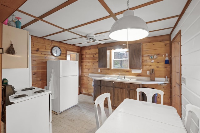 kitchen with wooden walls, decorative light fixtures, sink, ceiling fan, and white appliances