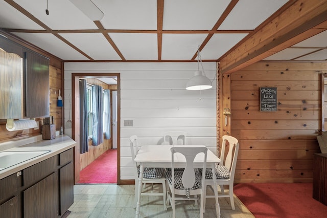 dining space with sink, light colored carpet, and wood walls