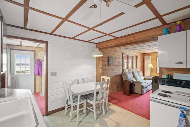 carpeted dining room with sink, ceiling fan, and wood walls