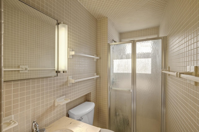 bathroom with tile walls, a shower with door, and toilet