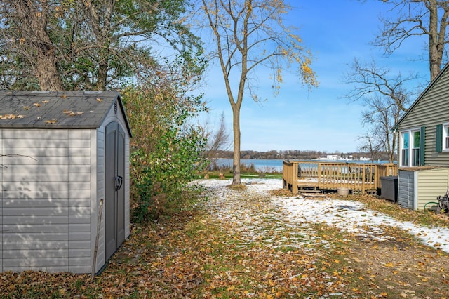 view of yard with a deck with water view and a storage unit