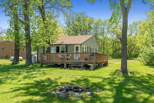 back of house featuring a wooden deck, a yard, and a shingled roof
