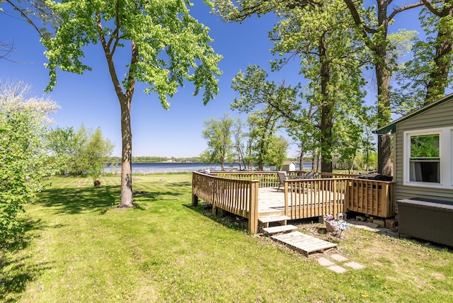 view of grassy yard with a deck with water view
