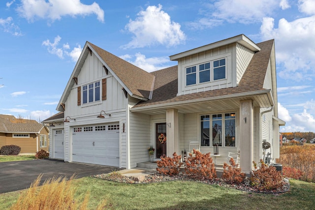 view of front of house featuring board and batten siding, roof with shingles, driveway, and a garage