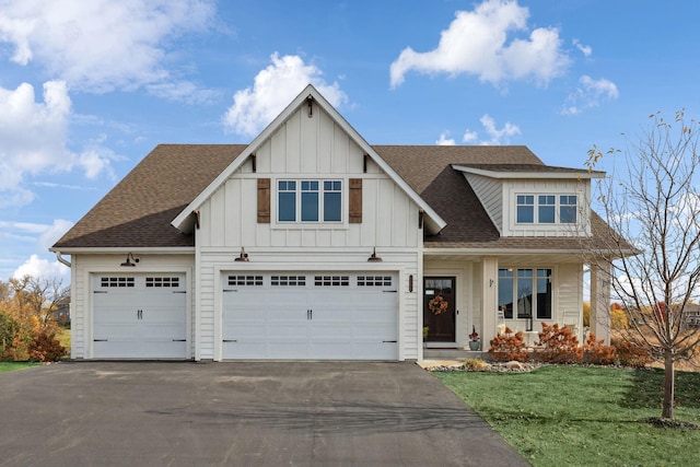 view of front of house featuring a shingled roof, a front lawn, aphalt driveway, and board and batten siding