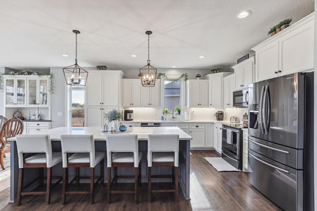 kitchen with a center island, a notable chandelier, stainless steel appliances, white cabinetry, and a kitchen breakfast bar