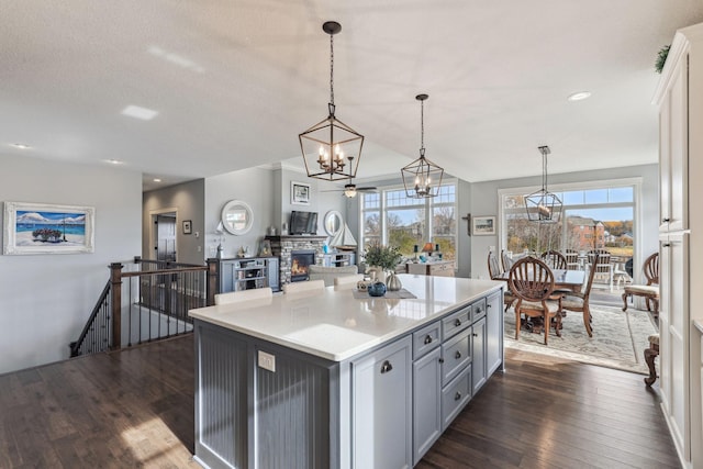 kitchen with dark wood finished floors, a kitchen island, gray cabinets, light countertops, and a fireplace