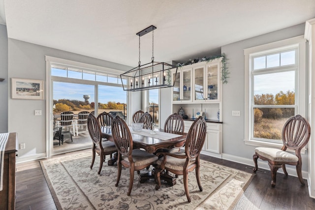 dining space featuring dark wood-style floors, baseboards, and an inviting chandelier