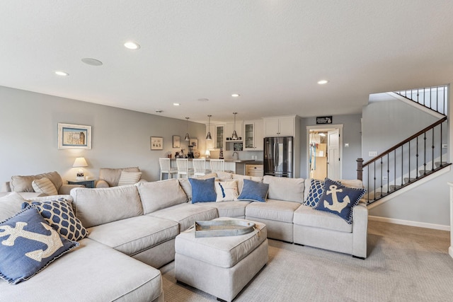 living room featuring stairs, baseboards, light carpet, and recessed lighting