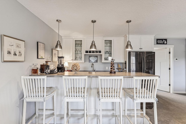 kitchen featuring glass insert cabinets, white cabinets, carpet flooring, and freestanding refrigerator