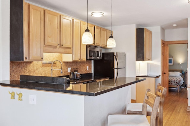 2701 Harriet Ave Unit 200, Minneapolis, MN 55408 - kitchen with appliances with stainless steel finishes, a peninsula, light brown cabinets, backsplash, and hanging light fixtures