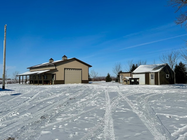 yard covered in snow featuring an outdoor structure and a detached garage